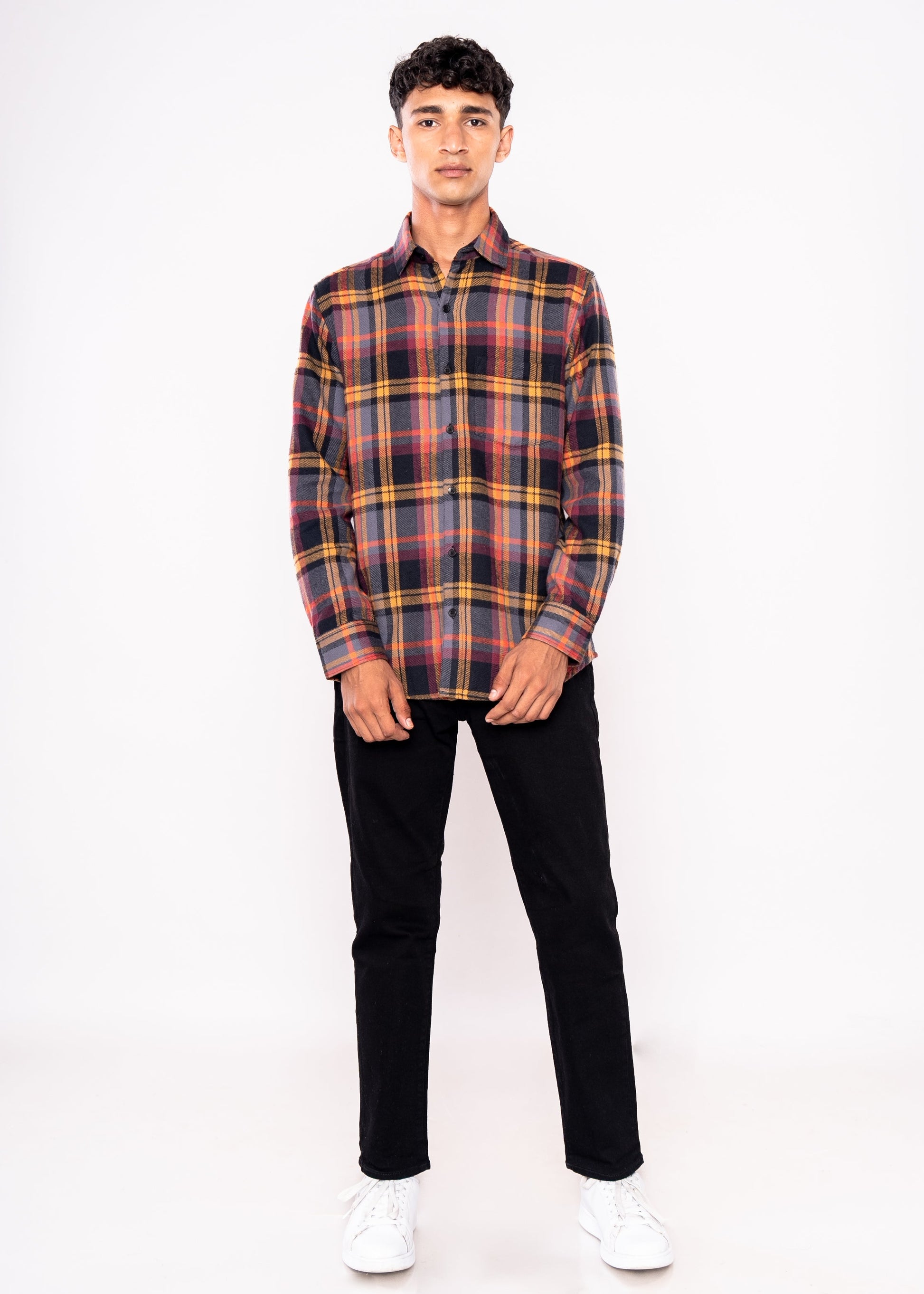 Person wearing a plaid shirt and black pants on a white background