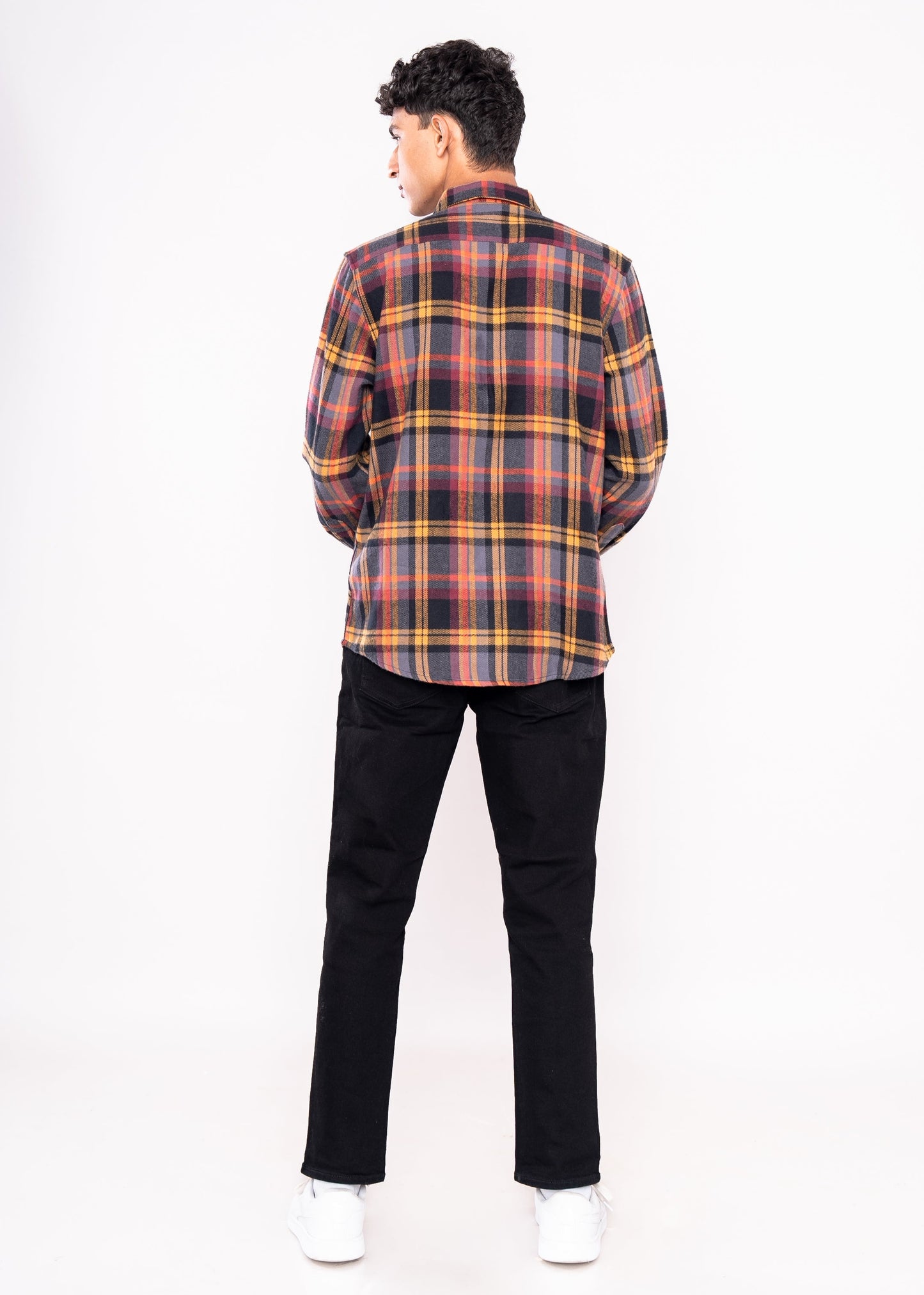 Person wearing a plaid shirt and black pants on a white background