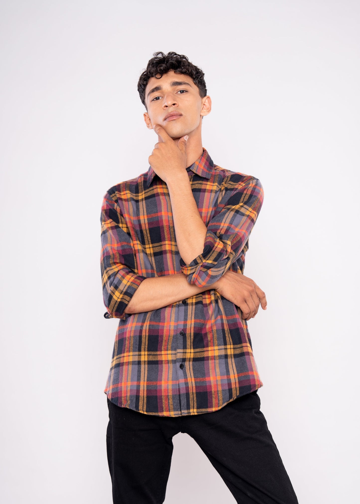 Person wearing a plaid shirt and black pants on a white background